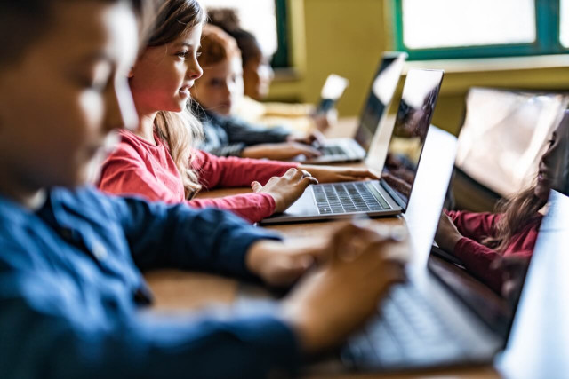 Een groep docenten en onderwijsprofessionals in gesprek, met een laptop en notitieblok op tafel, symboliserend samenwerking en carrièrekansen in het onderwijs.